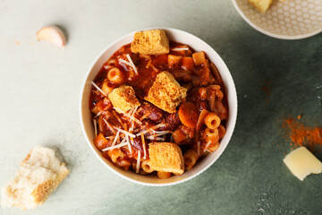 Bowl with tasty pasta and beans on color background