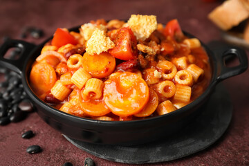 Dish with tasty pasta and beans on table