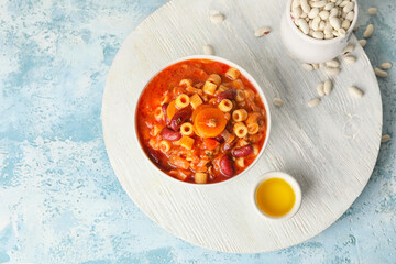 Bowl with tasty pasta and beans on color background