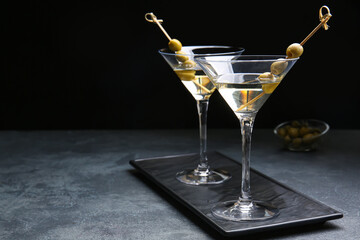 Glasses of tasty martini cocktail on dark background