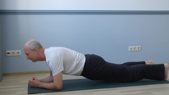 Athlete man doing plank exercise on yoga mat carpet at home training. Sportsman practicing plank workout while domestic fitness. Home gym exercise