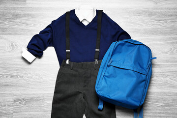 Stylish school uniform with backpack on wooden background