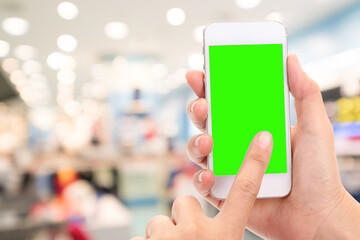 Woman hand click on green screen of mobile with blur supermarket background. Business online, delivery concept.