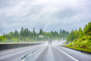 Big rig semi truck with flat bed semi trailer running on the wet road at raining weather with another traffic