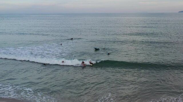 imagem aérea de bela praia com pessoas praticando surf, bodyboard, stand up e se banhando 