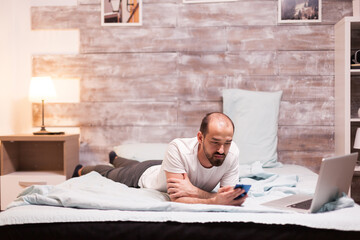 Fototapeta premium Using smartphone while laying on bed at night