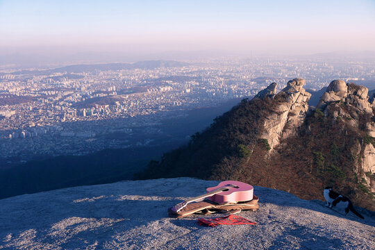 Panoramic view of Seoul city from Bukhansan Mountain. Hiking uphill with a guitar. Self-isolation of creative people. View from the top of the mountain to the city