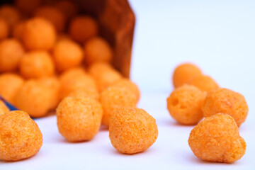 tasty cheese balls drop from packet on white background