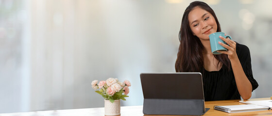 Female work from home Take short break with drinking coffee and looking on digital tablet
