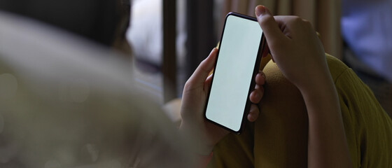 A girl using mock-up smartphone while sitting in living room beside balcony