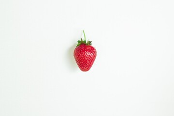 One ripe red strawberry on a white background