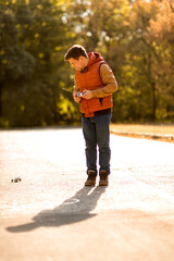 man in vest playing with toy car on remote control in autumn Park.