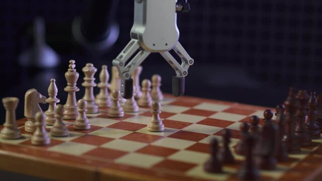 Modern technology, man playing chess with a robot, confrontation between man and artificial intelligence, futuristic robotic arm participates in the game, black background.