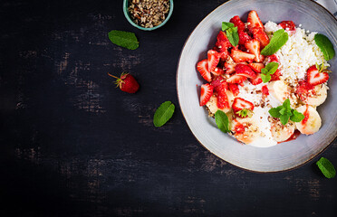 Cottage cheese or curd cheese with strawberries, bananas, walnuts in a blue bowl. Healthy food. Top view, overhead,  copy space