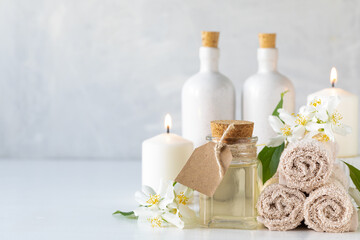 Fototapeta na wymiar Jasmine essential oil, candles and towels, flowers on a white background. Spa and wellness concept. Copy space.