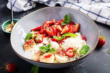 Cottage cheese or curd cheese with strawberries, bananas, walnuts in a blue bowl. Healthy food.