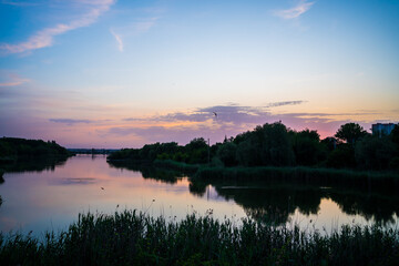 Naklejka premium beautiful evening landscape. sunset on river. calm water in pond.
