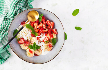 Cottage cheese or curd cheese with strawberries, bananas, walnuts in a blue bowl. Healthy food. Top view, overhead,  copy space