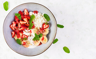 Cottage cheese or curd cheese with strawberries, bananas, walnuts in a blue bowl. Healthy food. Top view, overhead,  copy space