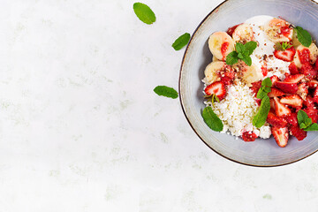 Cottage cheese or curd cheese with strawberries, bananas, walnuts in a blue bowl. Healthy food. Top view, overhead,  copy space