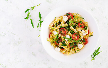 Pasta salad. Fusilli Pasta - Caprese salad with tomato, mozzarella and basil. Top view, flat lay,...