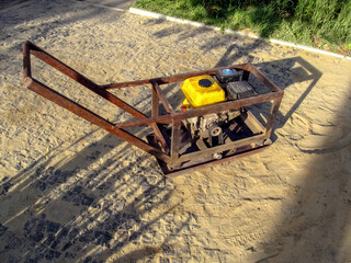 Home-made vibratory rammer stands on a site with newly laid granite paving stones. Do-it-yourself...