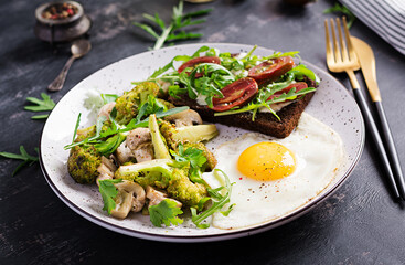 Breakfast with fried egg, broccoli, mushrooms and tomato sandwich. Healthy balanced food.