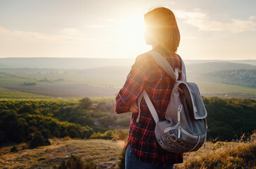 Young hipster girl enjoy sunset on viewpoint. Travel woman with backpack