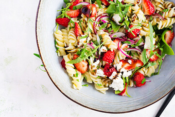 Pasta salad. Fusilli Pasta - salad with strawberry, feta cheese, red onion and balsamic sauce. Top view, flat lay, copy space