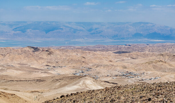 a group of bedouin villages can be seen in the hills between Arad in Israel and the Dead Sea with the Moab mountains of jordan in the background