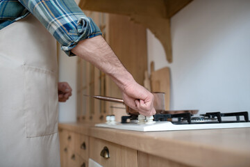 Man in a checkered shirt putting the pan on the oven