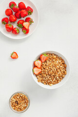 Homemade granola in a bowl with fresh strawberries, nuts and yogurt. Healthy and delicious Breakfast. The concept of summer food. Top view, selective focus.