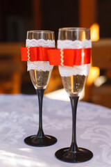 wedding glasses with champagne, tied with red ribbon