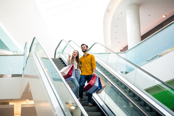Full length photo of excited shocked two people couple move staircase look incredible 50 sales girl point index finger hold many packages in shopping mall center
