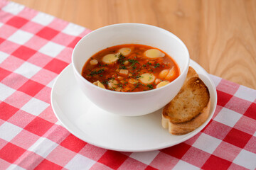 Chicken soup with vegetables and meat and macaroni served in a white bowl over rustic wooden...