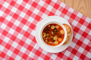 Chicken soup with vegetables and meat and macaroni served in a white bowl over rustic wooden...