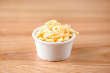 Cut cheese in a small white bowl. Snack, appetizer. Pizza ingredient.