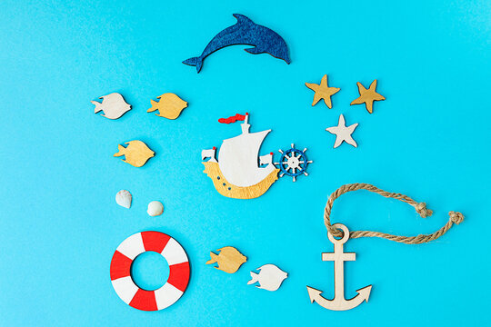 Summer composition in marine style, with shells and wooden figures on a blue background. Concept of summer vacation at the sea. flat lay, copy space.