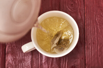 Tea bag in a white cup. Add boiling water to the cup. Making delicious herbal tea.