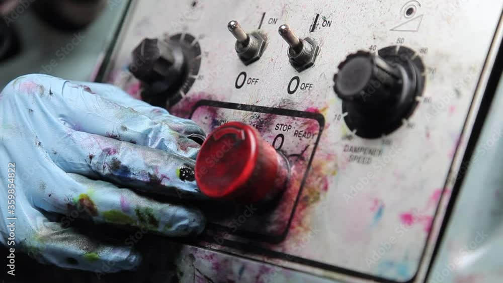 Poster hand in blue latex glove spattered with colorful ink pushes green start button on control panel then
