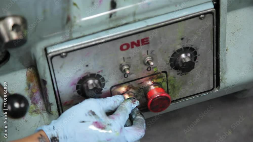 Aufkleber close up view of person operating a printing press by pushing green button to start then releasing. 