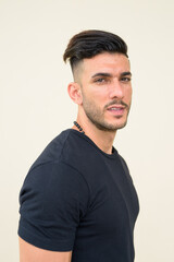 Obraz premium Profile view of young handsome bearded Persian man looking at camera