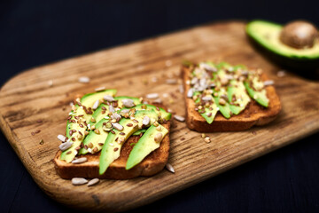 Toast with sliced avocado, mixture of seeds on a wooden background. Healthy snack tomorrow. The concept of proper nutrition, diet.