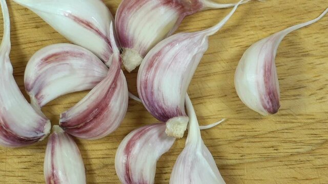 A bunch of garlic cloves on a wooden surface. Cooking