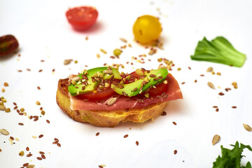 Ciabatta with jamon, prosciutto and avocado with tomato and vegetables on a white background. Healthy food concept.