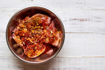 Raw rabbit in a bowl with spices. Marinate meat, preparing for cooking.