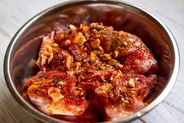 Raw rabbit in a bowl with spices. Marinate meat, preparing for cooking.