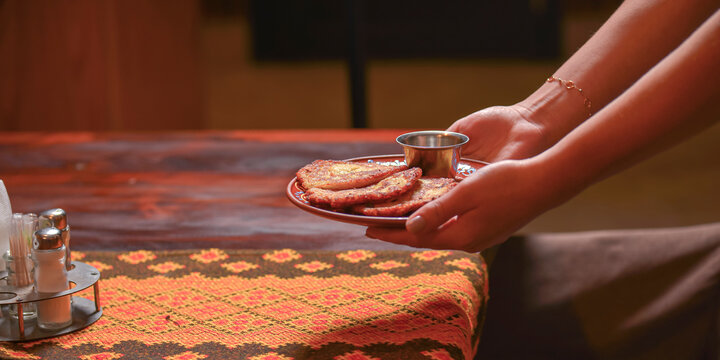 Potato pancakes dranik with sour cream, traditional Ukrainian dish. Waiter in traditional uniform serving dranyki.