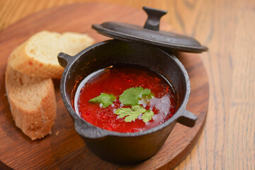 Traditional Ukrainian Russian vegetable borscht in a bowl with bread on the old wooden background. Traditional cuisine.