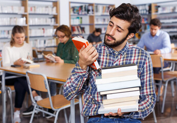 upset man with stack of books in hands